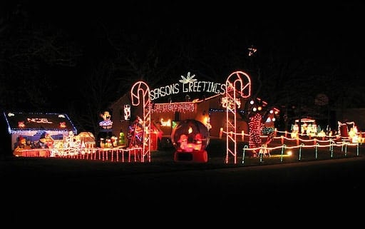 Holiday display with Christmas lights, arches, and animated figures glowing in the night