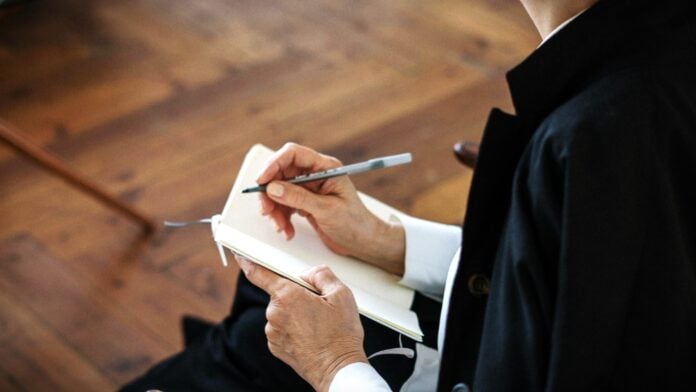 Woman in Black Blazer Holding White Note pad by cottonbro studio