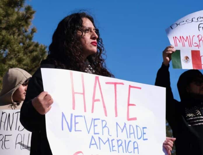 Monica Martinez holds up a sign that reads “Hate never made America great” as she faces main street in Garden City, Kansas. She and dozens of others gathered downtown for an immigrant rights rally in the predominantly Latino southwest Kansas town.