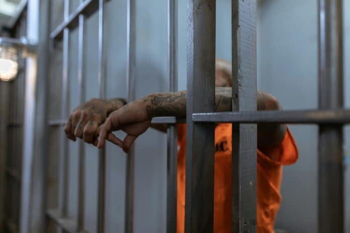 A Person in Orange Shirt with Tattooed Arms in Jail By RDNE Stock Photo Project