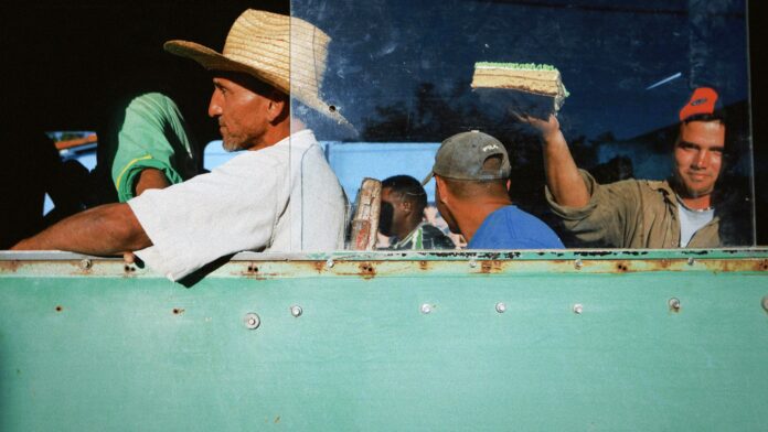 farm workers on a bus with cake after a long day in the midwest sun by Mehmet Turgut Kirkgoz