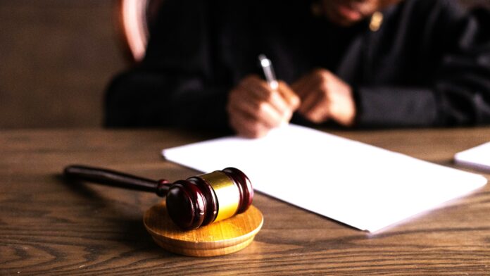 Judge Signing the Papers on their desk with a gavel By KATRIN BOLOVTSOVA