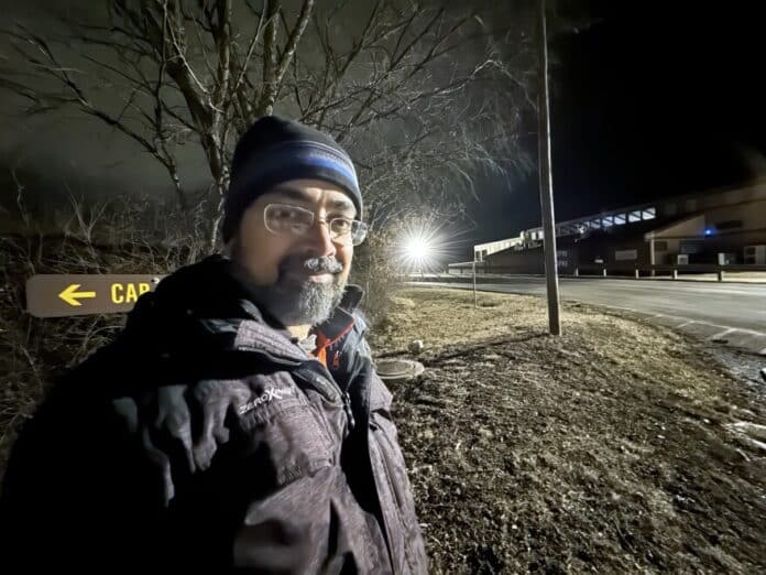 download (7) Astronomy professor Vayujeet Gokhale poses near a light that causes excessive glare, skyglow and disruption to wildlife at Thousand Hills State Park’s marina. The park is switching to lighting that works better for human eyes and the environment.
