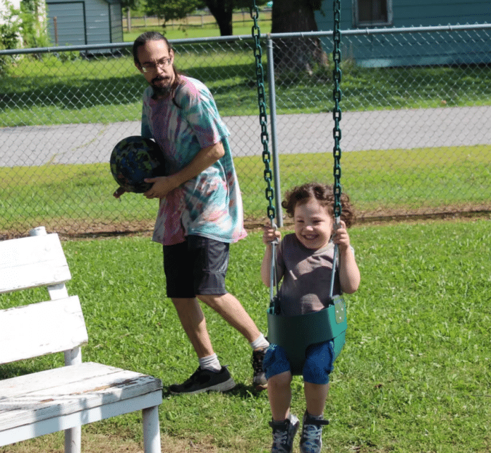 Steve Hench watches his three-year-old son, Oliver Hench, swinging in a park in Weir, Kansas.