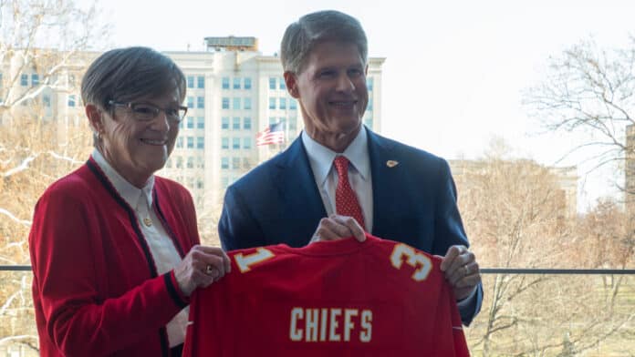 PC220319-2048x1152 Kansas Gov. Laura Kelly holds a Chiefs jersey with team owner Clark Hunt ahead of a news conference Dec. 22, 2025, at the Kansas Docking State Office Building in Topeka. (Photo by Anna Kaminski/Kansas Reflector)