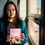 Jill Clements holds a photo of her daughter, Page. She finished high school early so she could move to Minnesota, where gender-affirming care is more accessible.