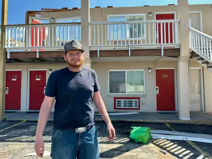 Kolton George stands in front of the Knights Inn Motel in Ottawa, Kansas. A Monday night tornado blew out the hotel’s roof, windows and parts of its walls.