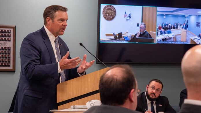 P3061041-2048x1152 Kansas Attorney General Kris Kobach argues against a restraining order before a Douglas County District Court judge on March 6, 2026. The case was filed by two men opposed to Kansas’ new law forcing transgender people to use their biological sex at birth when using the restroom or on state documents. (Photo by Sherman Smith/Kansas Reflector)