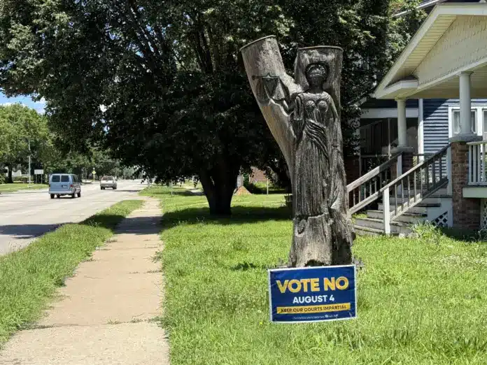 download (77) Zach Boblitt / Kansas Public Radio / Kansas News Service A keep our courts impartial sign sits in front of a tree stump carved lady justice — a blindfolded symbol which represents impartiality and objectivity — Something that people who oppose the amendment worry could be lost if justices are directly elected.